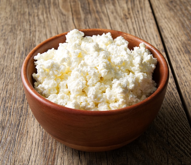 Brown wooden Bowl of homemade curd on dark brown wooden background