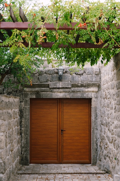 Foto un ingresso in legno marrone al cortile con un baldacchino di fiori ricci