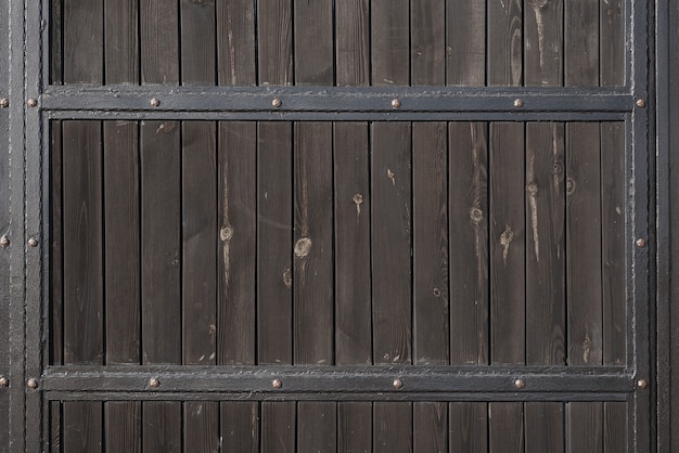 Brown wooden gate with forged metal stripes. Backgrounds and textures. Close up