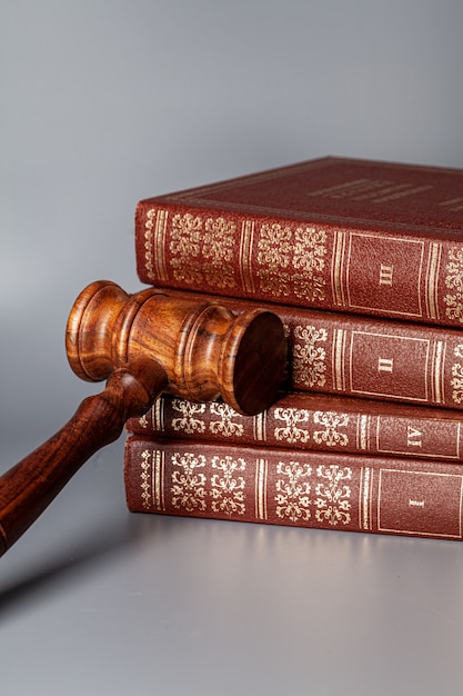 Brown wooden gavel with stack of books on gray table