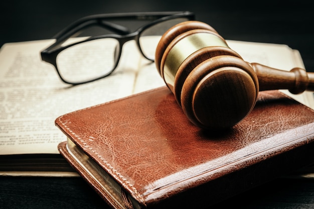 Brown wooden judge mallet on the background of open book