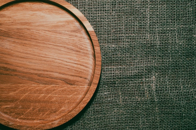 The brown wooden plate on a rustic table closeup.