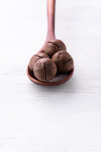 Foto cucchiaio di legno marrone con noci di macadamia su sfondo bianco per il catalogo