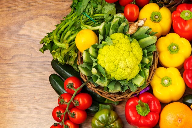 Photo a brown wooden table with a wicker basket and various types of vegetables