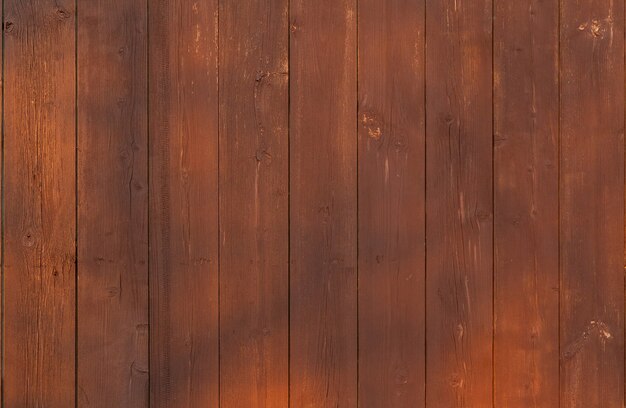 Brown wooden vertical plank fence with sun glare.