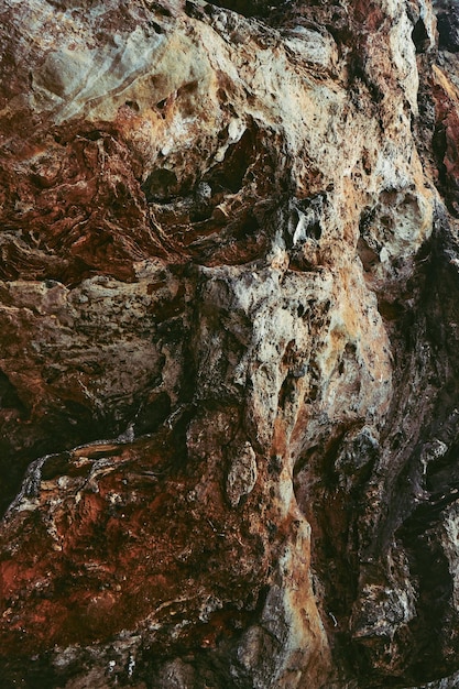 Photo brownblack stone wall of the cave as a background or a backdrop vertical image