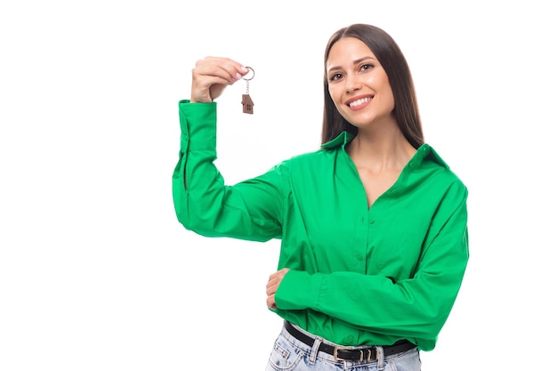 녹색 셔츠를 입은 브라운아이드 브루네트의 젊은 비즈니스 여성이 아파트 열쇠를 받았습니다.