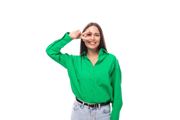 コピー スペースと白い背景に緑のシャツを着た茶色の目のブルネットの若いビジネス女性
