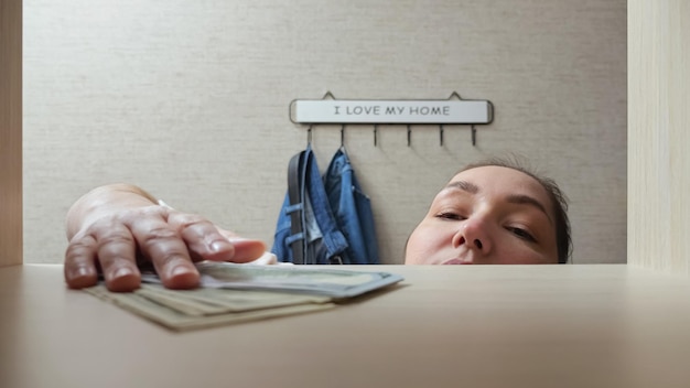 Brownhaired woman takes money banknotes from wooden shelf