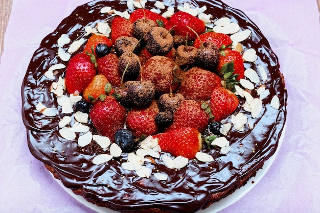 Brownie cake decorated with red berries on wooden table