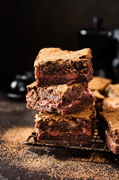 Brownie cheesecake cake with cherry and chocolate on a dark background. Selective focus.