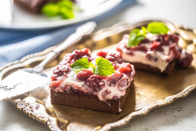 Brownie kersencakes met room, zure kersen en verse munt op een vintage dienblad.