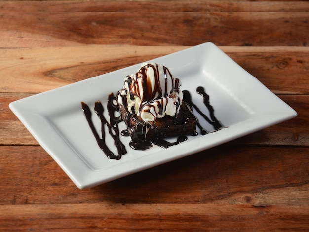 Brownie Sundae met een bolletje vanille-ijs Chocoladesaus Slagroom op wit bord