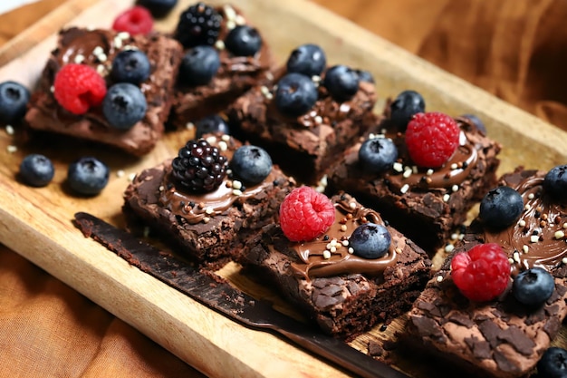 Brownie with berries and chocolate on a wooden board Homemade vegan brownies