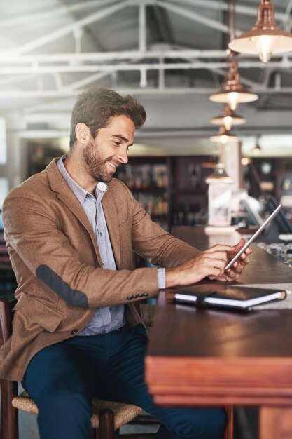 バーでブラウジングバーで彼のデジタルタブレットを使用してハンサムな若い男のトリミングされた肖像画