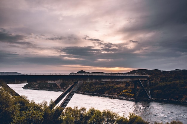 Brug over de rivier tegen de hemel bij zonsondergang