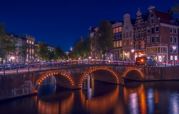 Brug over het kanaal te midden van verlichte gebouwen in de stad's nachts
