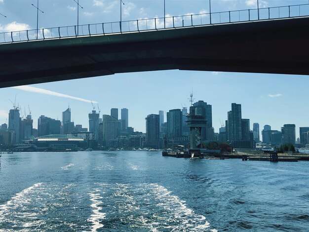 Foto brug over rivier door gebouwen tegen de lucht