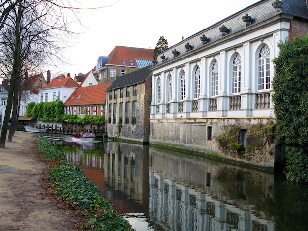 Brugge, Bruges typical street in old town, ancient houses with tiled roofs, canal, autumn, Belgium.