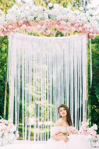 Bruid bij huwelijksboog met bloemen