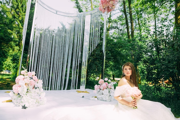 Bruid bij huwelijksboog met bloemen