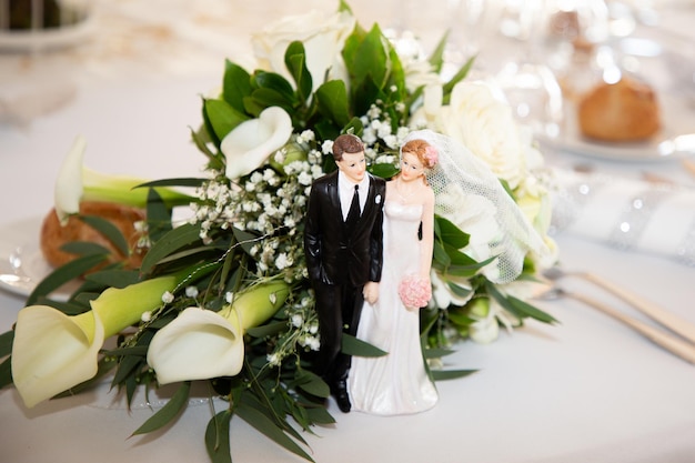 Bruid bloemen boeket geplaatst op de receptie tafel met beeldjes die het bruidspaar voorstellen