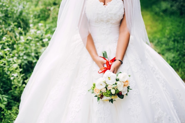 Bruid die een helder huwelijksboeket met verschillende bloemen houdt