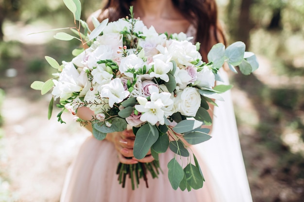 Bruid die een helder huwelijksboeket met verschillende bloemen houdt