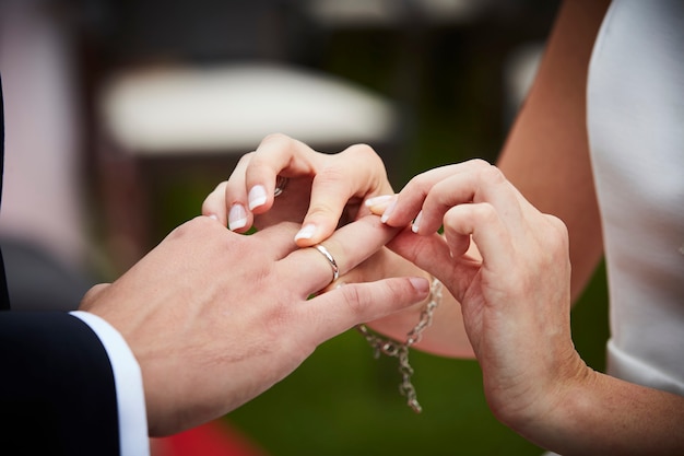 Bruid die trouwring op de vinger van een bruidegom zet