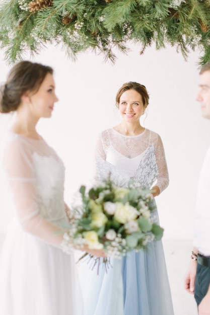 Bruid en bruidegom bij huwelijksceremonie met decoraties en dennenboog in rustieke stijl