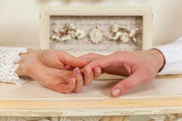Foto bruid en bruidegom, bruiloft, twee handen close-up tegen de achtergrond van engelen.