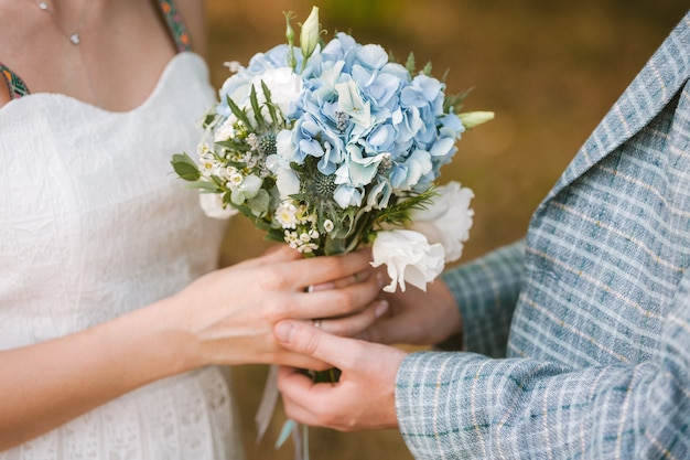 Bruid en bruidegom die mooi huwelijksboeket van bloemen houden