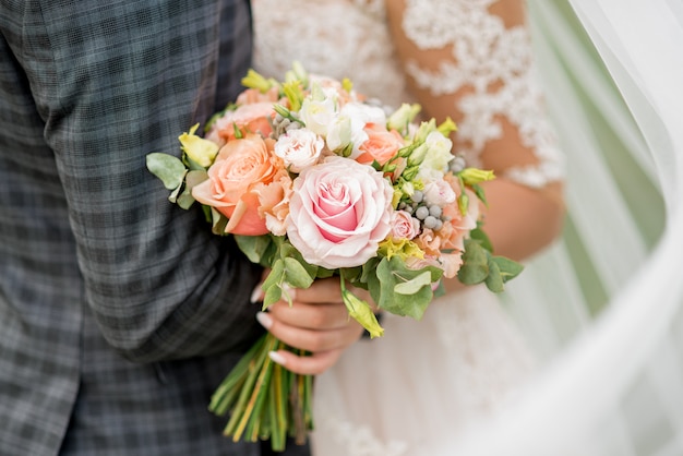 Bruid en bruidegom die mooi huwelijksboeket van bloemen houden