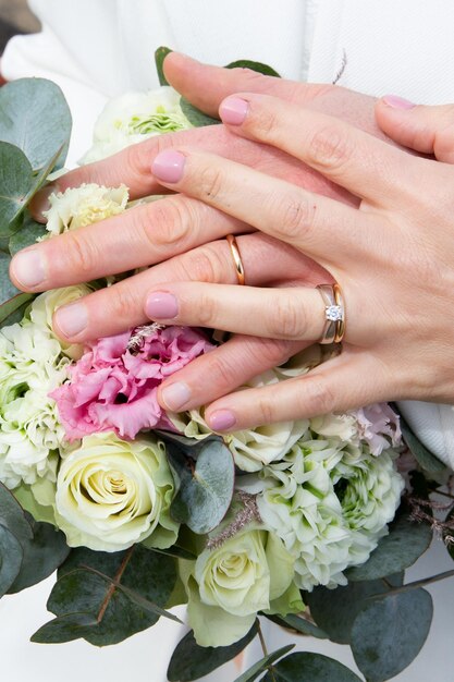 Bruid en bruidegom handen trouwringen close-up op boeket bloemen huwelijk