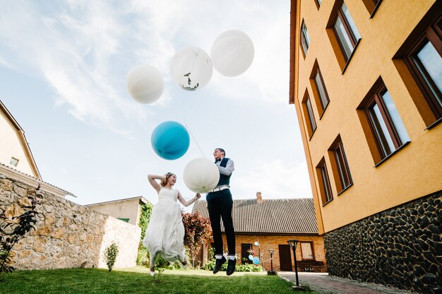 Bruid en bruidegom houden ballonnen in handen en springen.