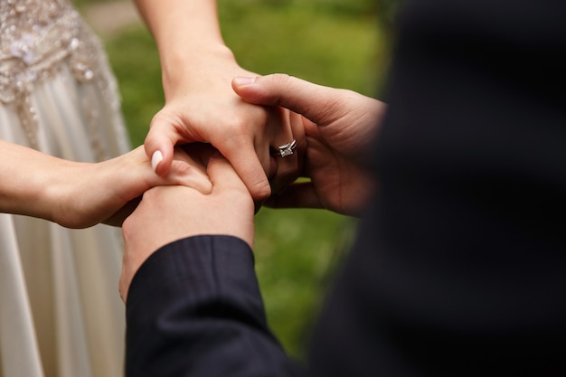 Bruid en bruidegom houden hun handen met trouwringen samen