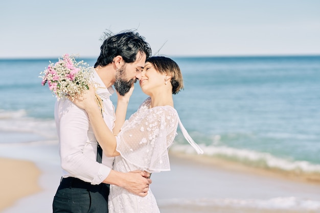 Bruid en bruidegom kussen op het strand die gelukkig hun huwelijk vieren