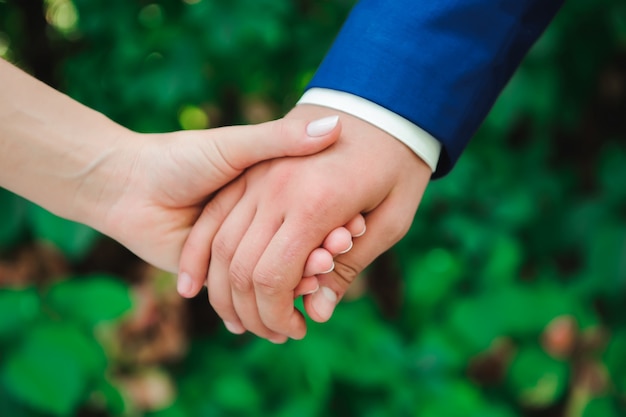 Bruid en bruidegom lopen hand in hand in het park