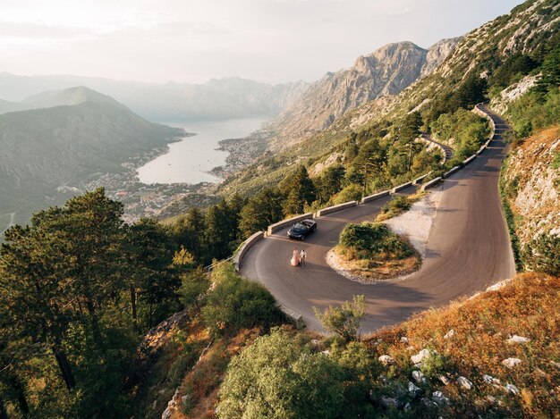 Bruid en bruidegom lopen langs een bergweg tegen de achtergrond van Kotor Bay drone