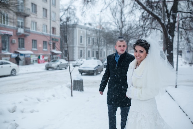 Bruid en bruidegom lopen op de Europese stad in de sneeuw