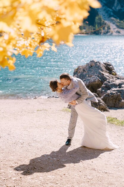 Bruid en bruidegom onder een herfstboom met vurig geel blad aan het lago di braies in italië