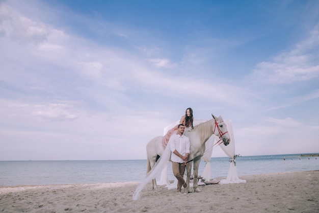 Bruid en bruidegom op strand met paarden. Trouwkoppel. Prachtig portret in de natuur