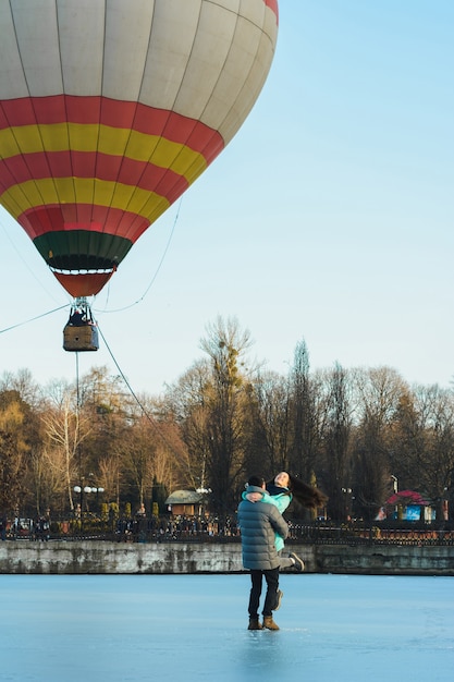 Bruid en bruidegom tegen de achtergrond van een bevroren meer en een ballon die in een stadspark vliegt.