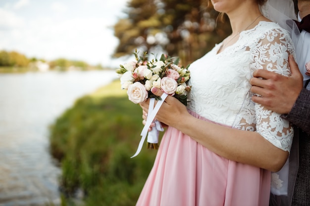bruid in een mooie jurk met een trein met een boeket bloemen en groen.