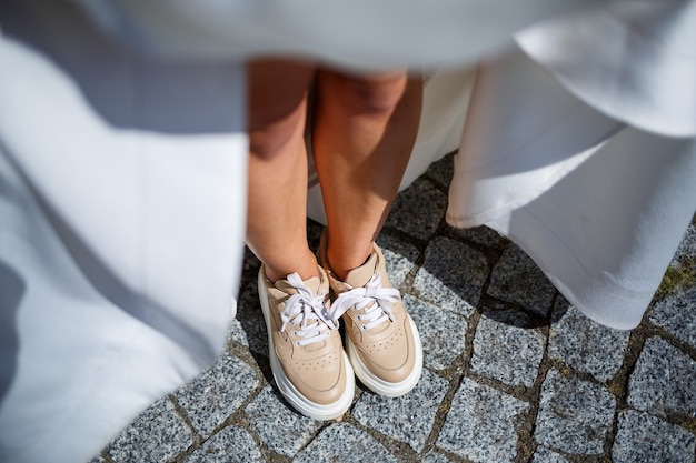 Foto bruid in een witte jurk en sneakers op een trouwdag