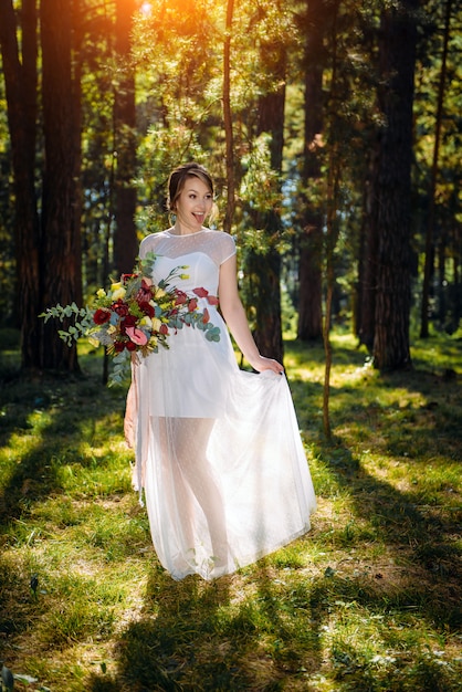 Bruid in een witte jurk met een boeket bloemen in haar handen