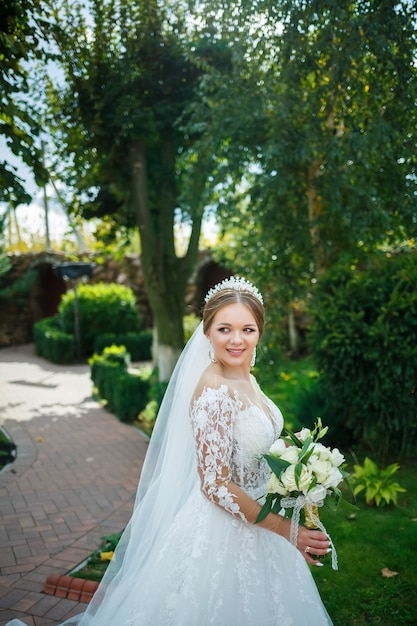 Bruid in een witte jurk met een boeket in haar handen en een kroon op haar hoofd