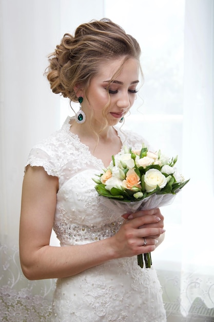 bruid in een witte jurk staat met een boeket bloemen