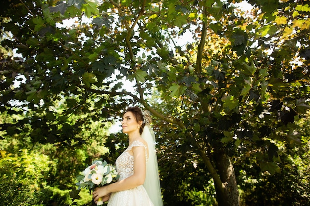 Foto bruid in mode trouwjurk op natuurlijke achtergrond. een mooi vrouwenportret in het park