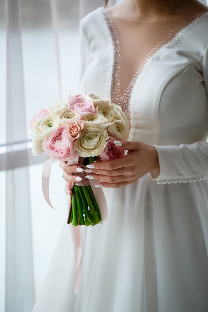 Bruid in witte jurk houdt een boeket bloemen vast